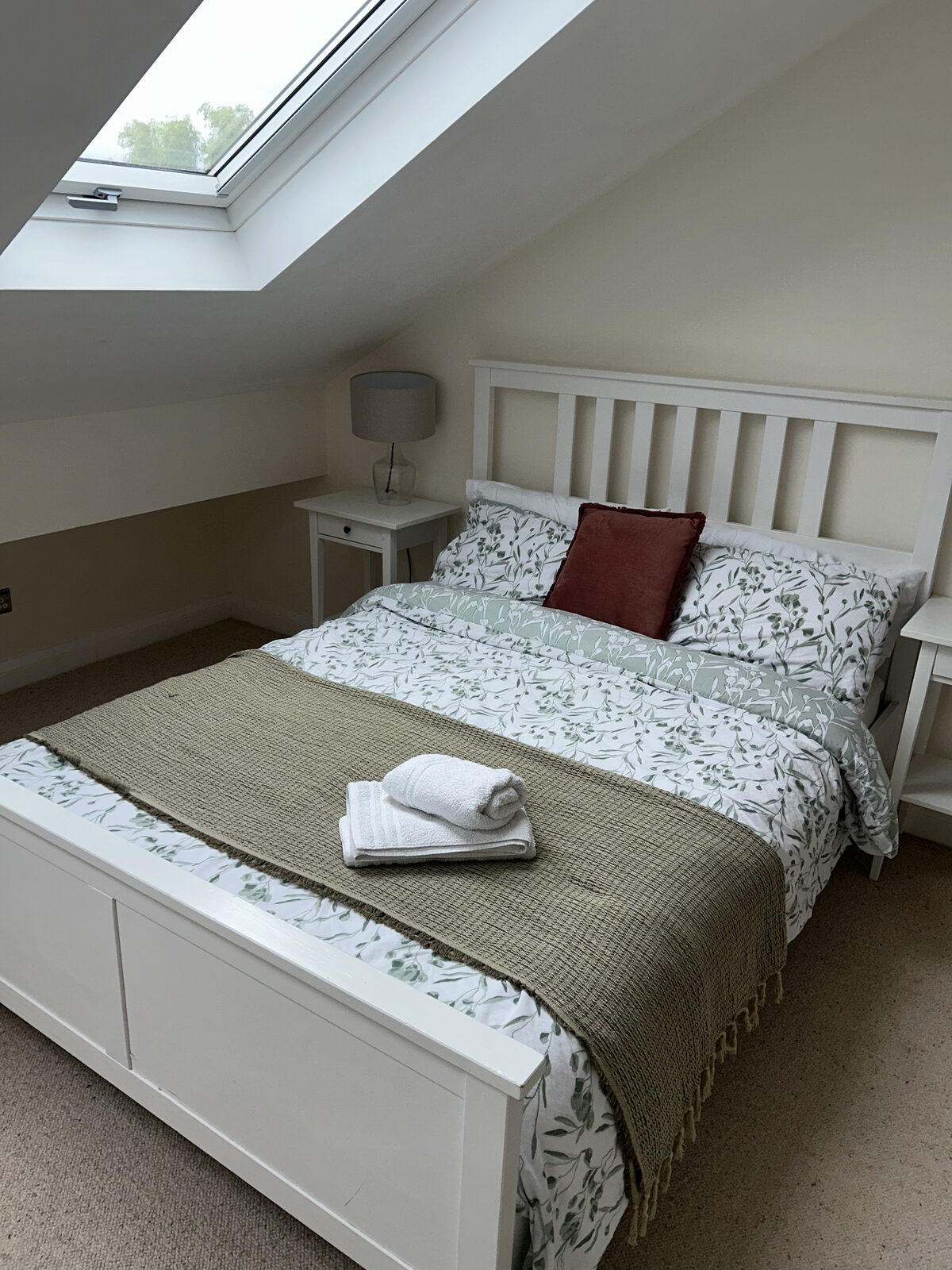 Freshly cleaned loft bedroom with white bed linen and skylight in Wigan