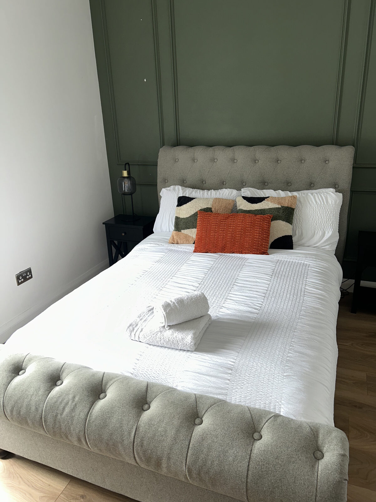 Clean and tidy guest bedroom with grey upholstered bed in Wigan